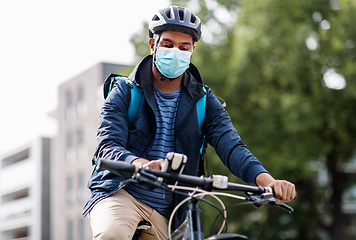 Image showing delivery man in mask with smatphone riding bicycle