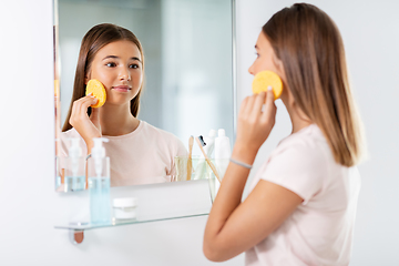 Image showing teenage girl cleaning face with sponge at bathroom