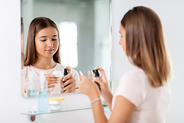 Image showing teenage girl applying lotion to cotton disc