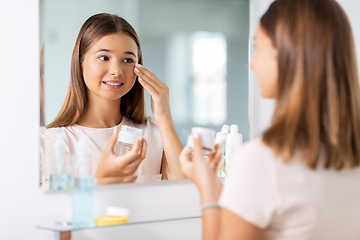 Image showing teenage girl with moisturizer at bathroom