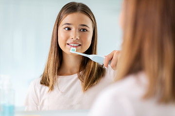 Image showing teen girl with electric toothbrush brushing teeth