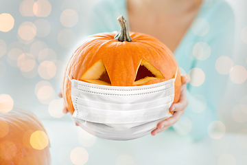 Image showing close up of woman holding pumpkin in mask