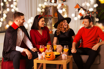 Image showing happy friends in halloween costumes at home party