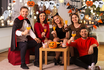 Image showing happy friends in halloween costumes at home party