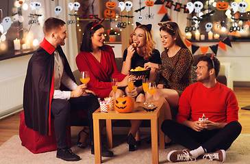 Image showing happy friends in halloween costumes at home party