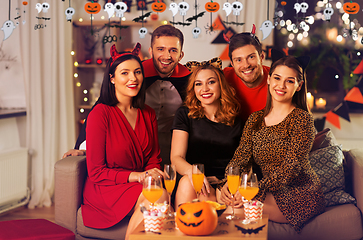 Image showing happy friends in halloween costumes at home party