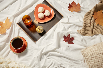 Image showing cup of coffee, autumn leaves and candle in bed