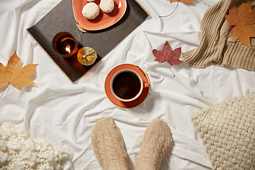 Image showing cup of coffee, autumn leaves and candle in bed