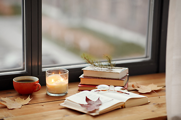 Image showing book, coffee and candle on window sill in autumn