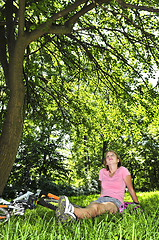Image showing Teenage girl relaxing in a park with her bicycle