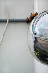 Image showing cityscape reflected on convex parking mirror