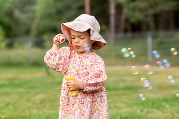 Image showing happy baby girl blowing soap bubbles in summer