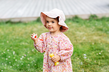 Image showing happy baby girl blowing soap bubbles in summer