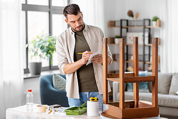 Image showing man with old table writing to notebook at home