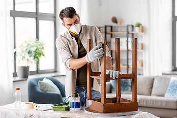 Image showing man in respirator sanding old table with sponge