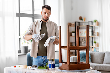 Image showing man applying solvent to rag for cleaning old table