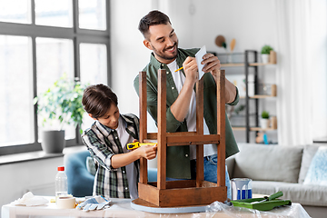 Image showing father and son with ruler measuring old table