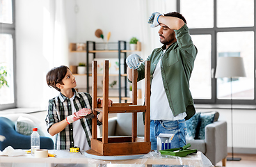 Image showing tired father and son sanding old table with sponge