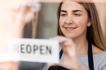 Image showing happy woman hanging reopen banner to door glass