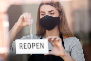 Image showing woman in mask with reopen banner on door glass