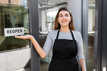 Image showing happy woman showing reopen banner on door glass