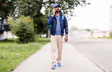 Image showing indian delivery man with bag calling on smartphone