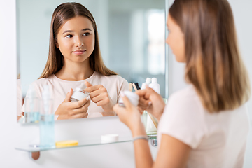 Image showing teenage girl with moisturizer at bathroom