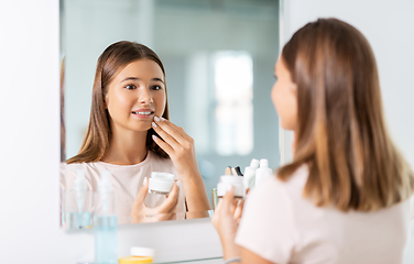 Image showing teenage girl with moisturizer at bathroom