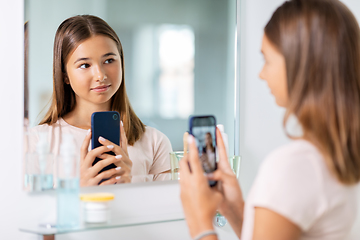 Image showing teenage girl looking in mirror and taking selfie