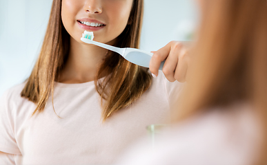 Image showing teen girl with electric toothbrush brushing teeth