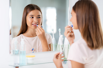 Image showing teenage girl applying lipstick at bathroom