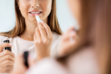 Image showing teenage girl applying lipstick at bathroom