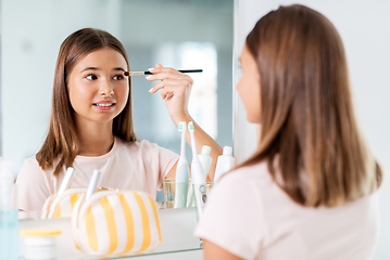 Image showing teenage girl applying eye shadow at bathroom