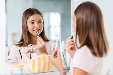 Image showing teenage girl applying lip gloss at bathroom