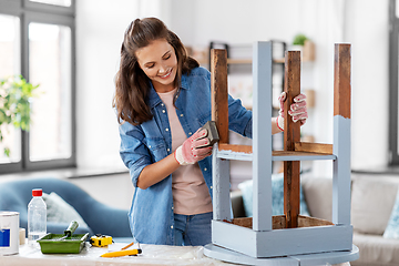 Image showing woman sanding old round wooden table with sponge