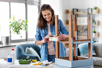 Image showing woman sticking masking tape to table for repaint