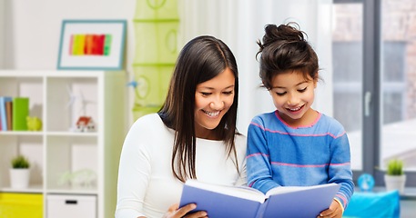 Image showing happy mother and daughter reading book at home