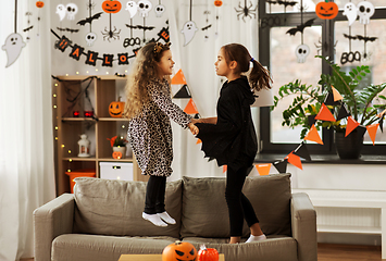 Image showing girls in halloween costumes jumping on sofa