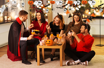 Image showing happy friends in halloween costumes at home party