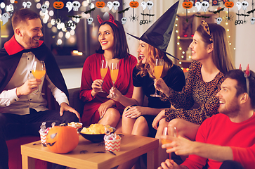 Image showing happy friends in halloween costumes at home party