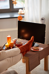 Image showing young woman watching tv at home on halloween