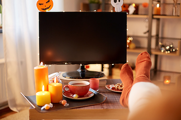 Image showing young woman watching tv at home on halloween