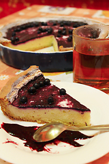 Image showing Piece of pie with bilberry on the plate and cup of tea