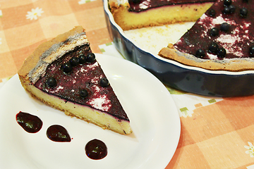 Image showing Piece of pie with bilberry on the plate and cup of tea