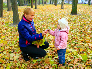 Image showing woman gives her daughter a sweet in the autumn park