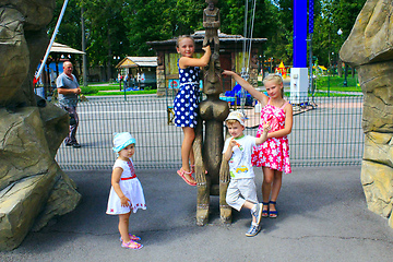 Image showing children play near the fabulous wooden statue