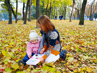 Image showing little sisters read the book in the autumn park