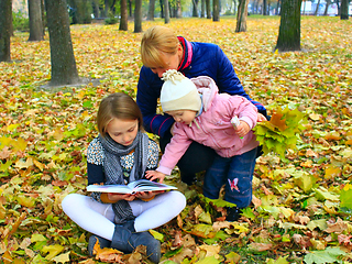 Image showing Mother with her daughters read a book in the park