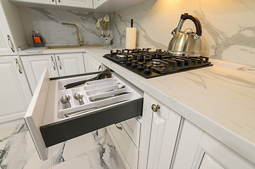 Image showing Open drawers with kitchenware at modern white kitchen