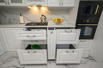 Image showing Open drawers with kitchenware at modern white kitchen